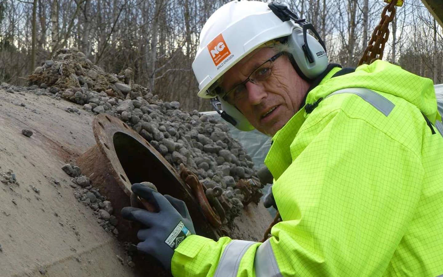 Arbeider fra Norsk Gjenvinning som inspiserer en oljetank. Foto.