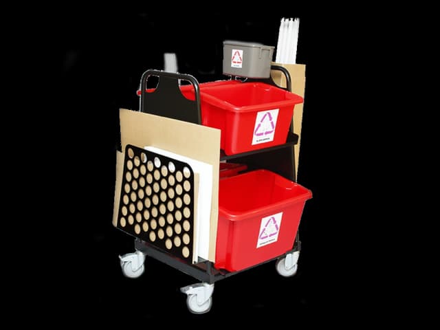 Tralle med fire hjul, fire rød plastbokser og pappholder. Foto.