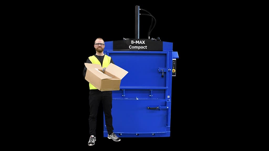 Blå B-MAX Compact emballasjepresse fra Europress med mann stående foran som holder en pappeske. Foto.