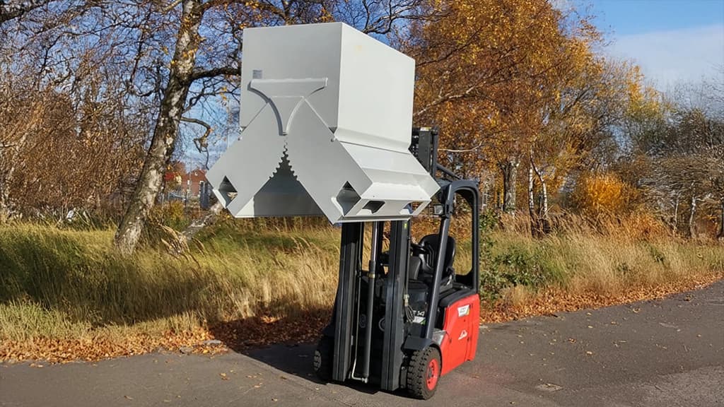 Gaffeltruck løfter en liten container. Foto.