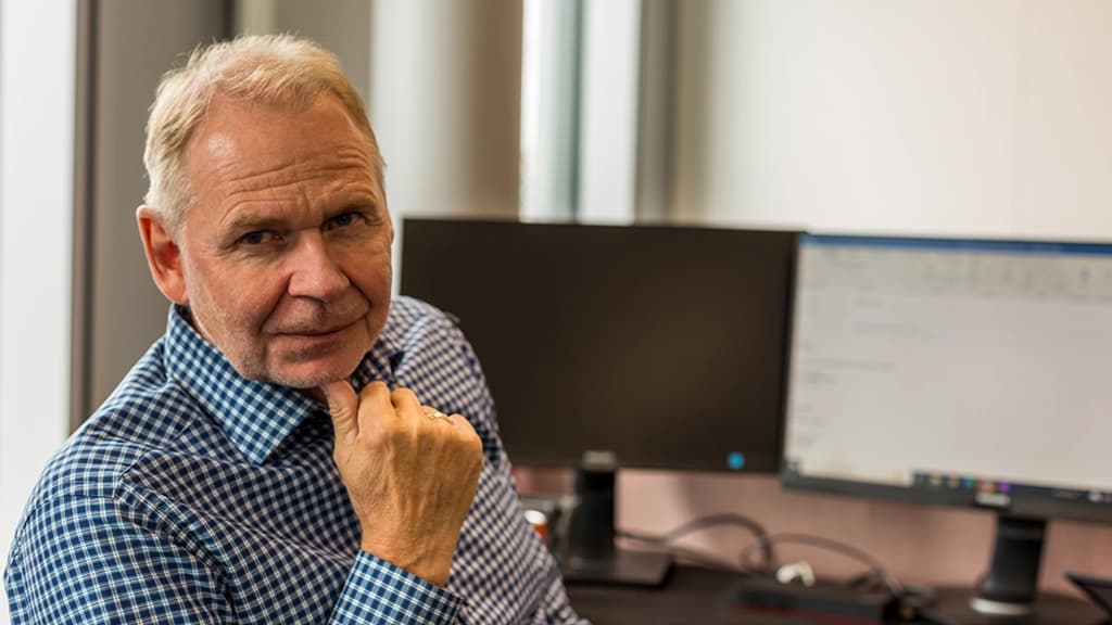 Mann på kontor foran PC. Foto.