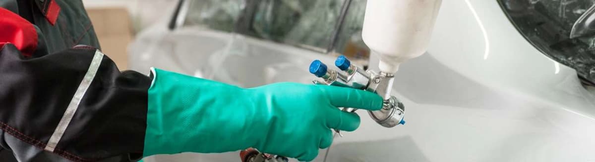 Hånd med plasthanske jobber med gassflaske. Foto.