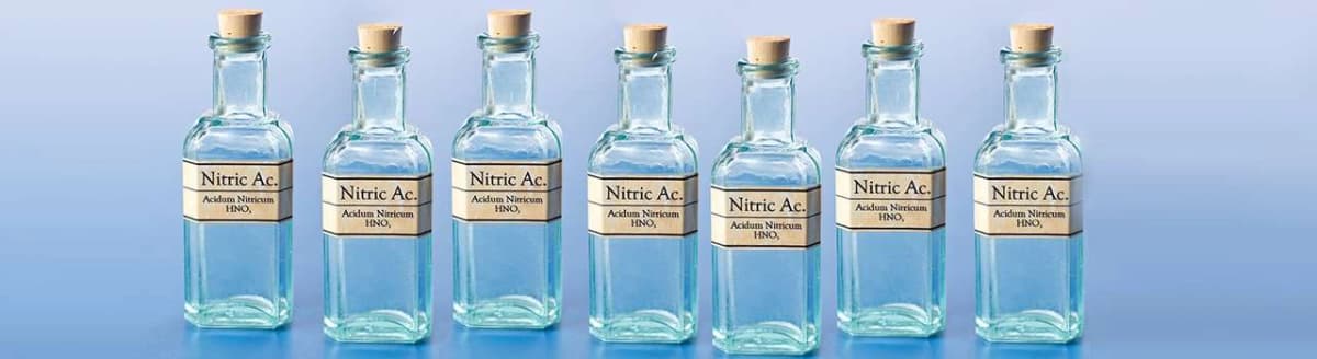 Glassflasker med etiketter for syrer. Foto.