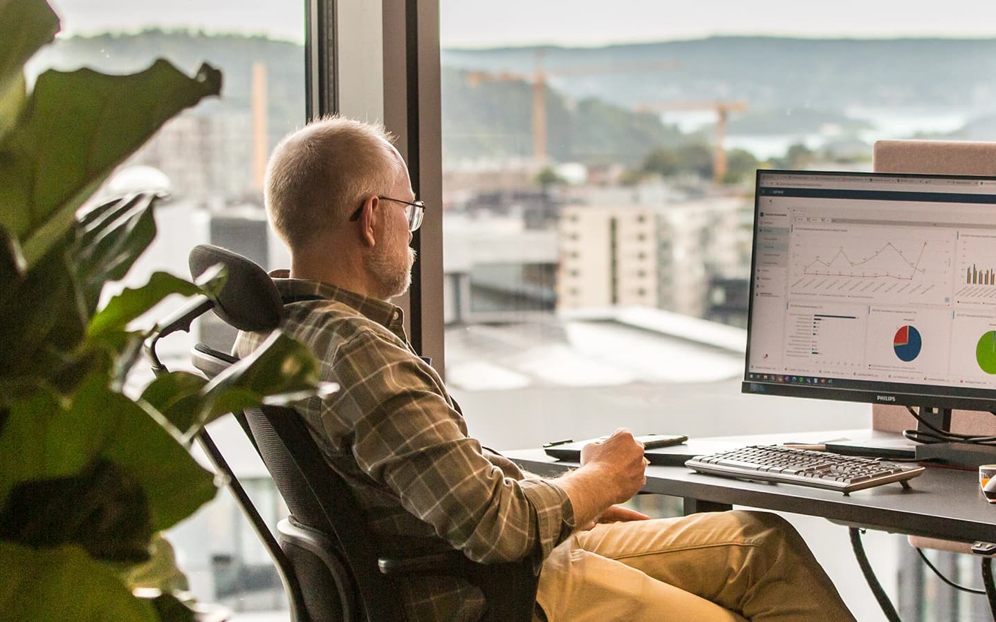 Mann på kontor foran PC. Foto.