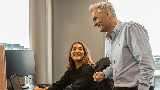 To smilende glade mennesker som har en prat i kontorlandskapet