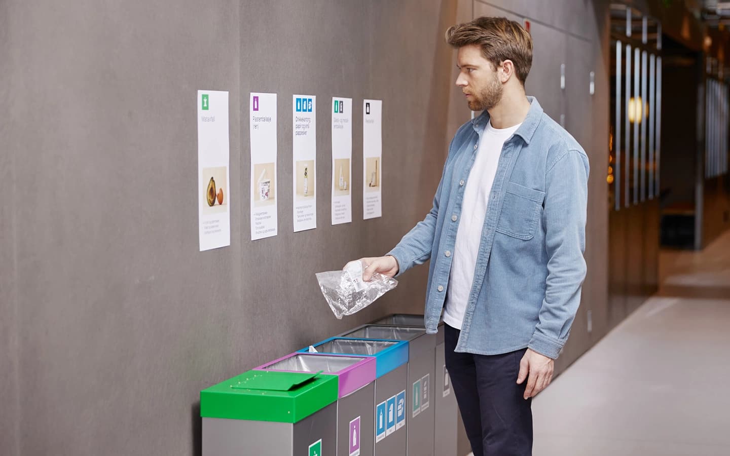 Mann kaster avfall på jobb i avfallsbeholder for plast. Foto.