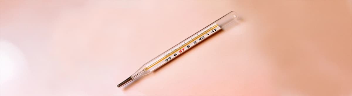 Termometer på rosa bakgrunn. Foto.