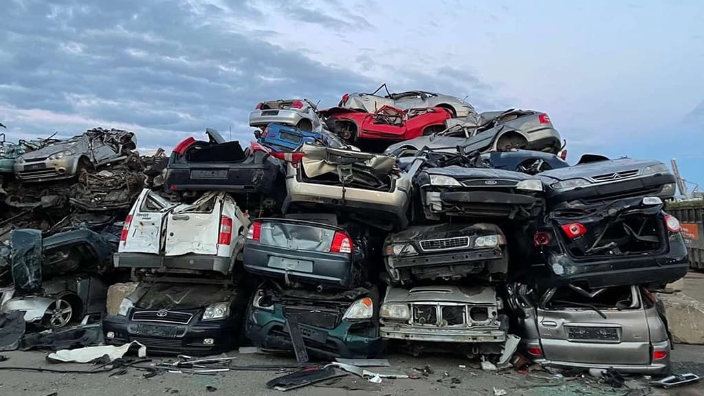 Vrakbiler ligger oppå hverandre i en haug. Foto.